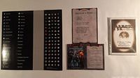 Group shot of sticker sheet, three reference cards, sealed rulebook