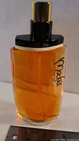 Front view of Mackie tester bottle showing amber liquid and logo