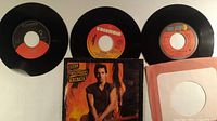Overview of three 7-inch records with labels visible and Bruce Springsteen picture sleeve