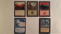 Five Magic: The Gathering cards laid out: Plains, Forest, Mountain, Narcomoeba, Rag Man