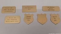 All seven brass plates laid out showing engravings and shapes