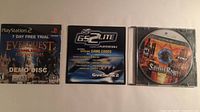 Front view of three discs: PS2 EverQuest demo, PS2 GameShark 2 Lite, Xbox 360 Saints Row