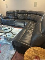 Full view of the L-shaped dark blue leather sectional couch with visible electric reclining sections and center console with cup holders, shown placed in a living room with wood flooring.