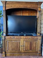 Front view of the solid wood Ethan Allen Tuscan craftsman style media cabinet with Mitsubishi TV raised in lift position.