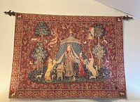 Front view of large rectangular woven tapestry depicting a lady flanked by a lion and a unicorn, background of stylized trees and banners
