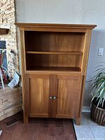 Front view of closed solid cherrywood bookcase with upper open shelf and lower double door cabinet.