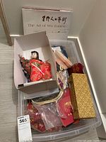 Wide shot showing assortment of Asian memorabilia including figurines in box and the art book 'The Art of Wu Zuoren' laid behind the container.