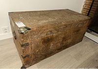 Front and top view of a large rectangular carved hardwood trunk with metal corner brackets and latch, showing overall condition and size