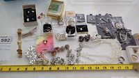 Overview of the assorted costume jewelry collection showing earrings, rings, necklaces, bracelets laid out with measuring tape for scale.