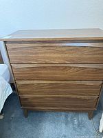 Front view of the four-drawer dresser showing wood grain finish and curved integrated drawer pulls.