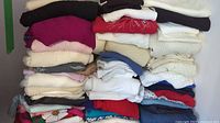 Stack of various folded ladies tops in multiple colors and fabrics.
