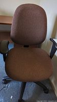 Front view of brown fabric office chair showing seat, backrest, and right armrest.