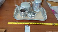 Full tea set with tray on wooden table with measuring tape indicating size.