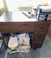 Front view of wooden sewing cabinet with drawer and fabric piles underneath