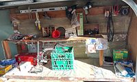 Wide view showing workbench with tools, toolbox, and miscellaneous items including yard bags and funnel