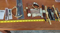 Full view of all watches and watch parts laid out with measuring tape below for scale