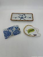 Three decorative trays displayed with ruler for scale, showing dimensions and design details