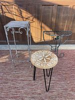 All three metal and wood plant stands placed next to each other on a textured rug in front of a wooden door showing size and design details