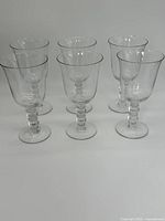 Full set of six clear glass water goblets arranged in two rows on a white background, showing the overall uniformity and style of the lot.