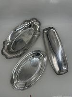 Three small silver plated serving platters arranged together showing different shapes and styles.