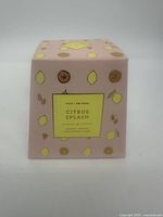 Decorative boxed Citrus Splash scented candle with citrus fruit illustrations on pastel pink background