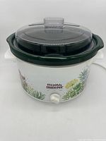 Front view of Rival Crock Pot with herb garden design on white base, glass lid, and control dial.