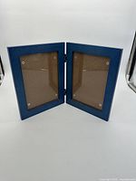 Blue double hinged wood photo frame shown open, capable of holding two photos side by side