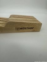 Close-up of the Wüsthof branded side profile of the beechwood utensil holder showing engraved logo.