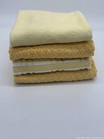 Stack of four yellow and white kitchen towels showing textured fabrics and white edges.
