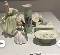Overview of all fine china figurines and decorative items including two figurines, vase, box, and dishes.