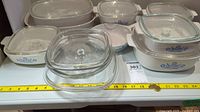 Top clear view of 7 casserole dishes including 4 CorningWare with blue cornflower pattern and three clear glass dishes with lids