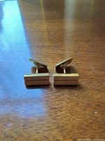 Front view of both cufflinks on wood surface showing rectangular bar design and bullet backs