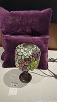 Front view of purple cushions and stained glass lamp on table