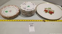 Photo showing all plates and serving platter with a measuring tape under for scale.