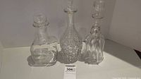 Front view of three decanters showing various shapes and the chip on one glass decanter.