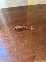 Photo of the brooch and pendant on a wooden surface.