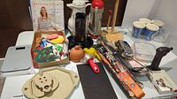 Photo showing a variety of cooking utensils including a cookbook, utensils, molds, and a black coffee dispenser.