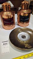 Photo of two copper vintage replica lanterns with colored lenses and nautical barometer on the table