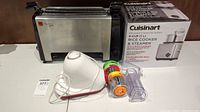 Photo showing the vertical grill in stainless steel and black, the Cuisinart boxed rice cooker and steamer, and Tfal Fresh Express+ vegetable grinder with attachments.