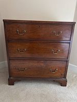 Front view of the mahogany chest showing three drawers with brass bail handles