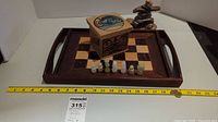 Wooden tray with chess board, chess pieces, whale box, and rock Inukshuk sculpture with measuring tape showing approximate tray length 17 inches