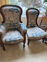 Two vintage chairs side by side near window showing overall view of upholstery and frame style.