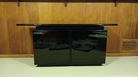 Front view of black lacquer buffet cabinet with glass top showing its high gloss finish and two main cabinet doors.