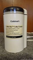 Side view of Cuisinart Coffee Bar coffee grinder showing brand and label with features.
