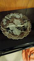 Crystal platter with floral motif, scalloped edges, and four sections, photographed on black surface with wood background.