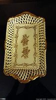 Top view of rectangular cream-colored china serving dish with lattice openwork and gold floral central design.