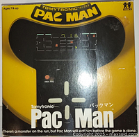 Front view of the original boxed 1981 Tomytronic Pac-Man handheld electronic game showing distinct yellow and black coloring and game controls.