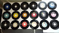 Top view showing 20 45rpm vinyl records laid out in rows with various label colors and brands.