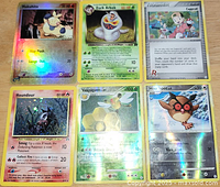 Six foil Pokemon cards arranged in two rows of three showing Pokemon characters Makuhita, Dark Arbok, Copycat Trainer, Houndour, Vespiquen, and Hoo Hoot.
