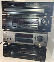 Stacked view of four audio components: Kenwood CD player top, JVC receiver second, RCA receiver third, Sony receiver bottom. Showing front panels with controls and displays.